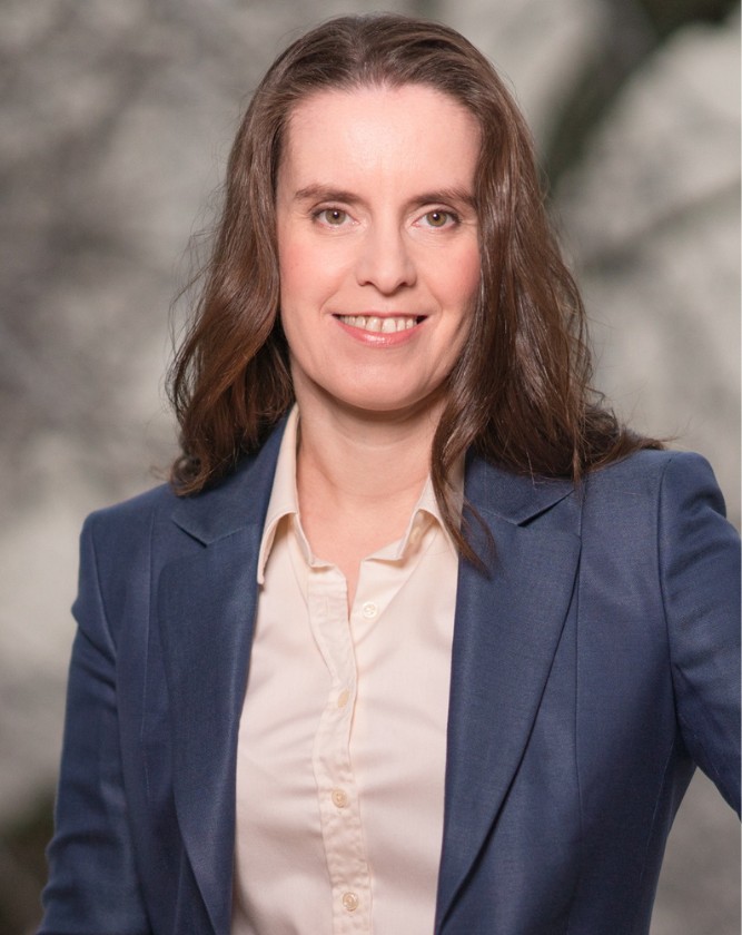 Stefanie mit offenen, langen, braunen Haaren, rosa Bluse und blauem Blazer.