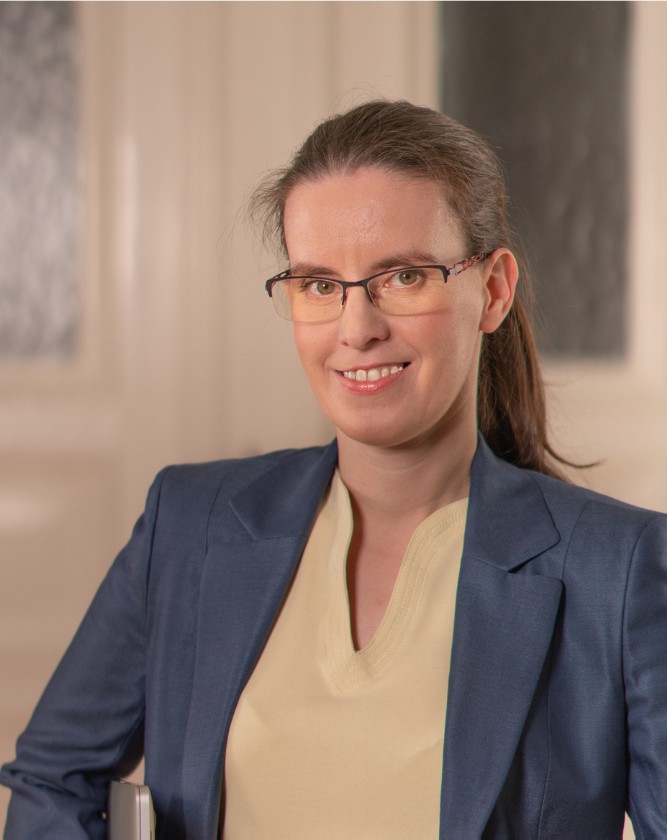 Stefanie mit Zopf, gelben Shirt und blauem Blazer.